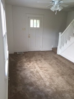 A room with a carpeted floor and a ceiling fan.