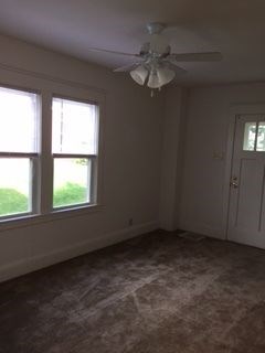 A room with a ceiling fan and two windows.