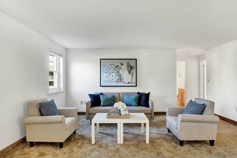 A living room with a large painting on the wall and a coffee table in the center.