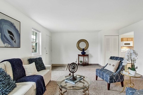 A living room with a white couch, a blue chair, and a glass coffee table.