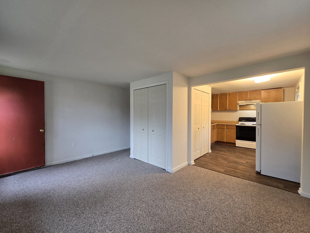 A room with a red door and a carpeted floor.