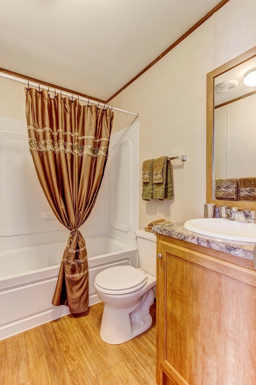 A bathroom with a toilet, sink, and brown curtains.