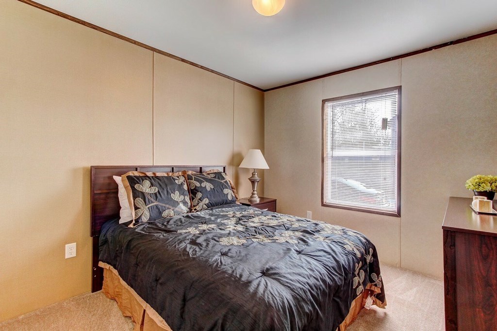 A bedroom with a bed, nightstand, and window.