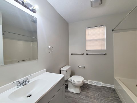 A bathroom with a toilet, sink, and mirror.