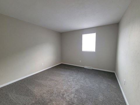 A room with a carpeted floor and a window.