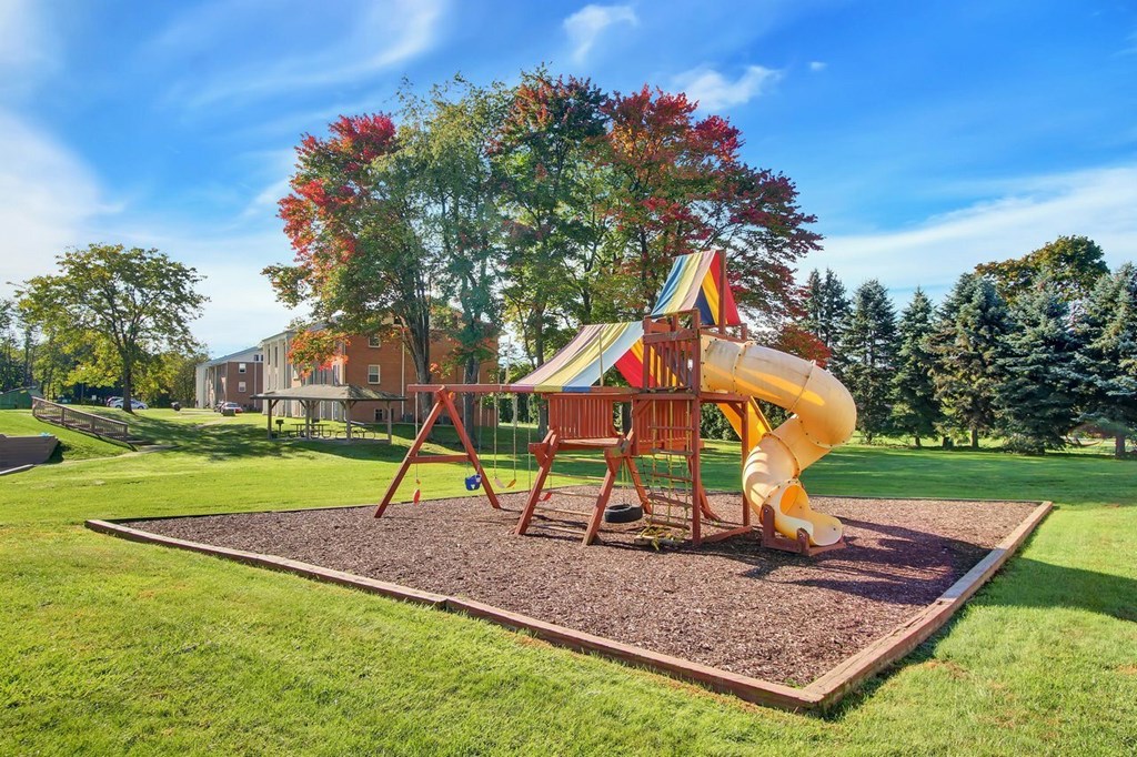 A playground with a yellow slide and a red and yellow canopy.