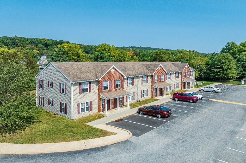A parking lot in front of a building with a red car parked.