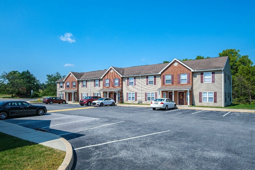 A parking lot in front of a multi-story apartment building.