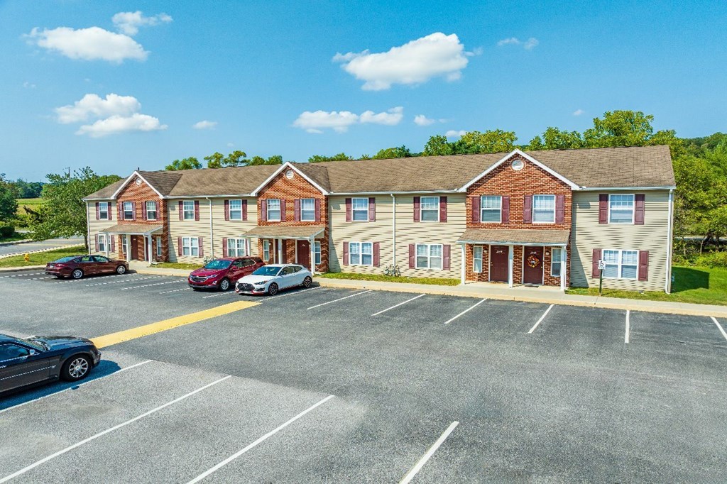 A parking lot in front of a two-story brick apartment building.