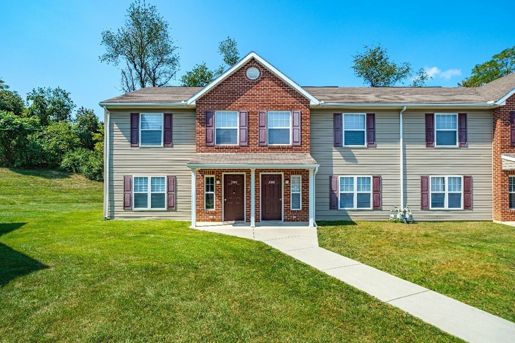 A two-story house with a red door and brown trim.