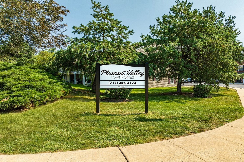 A sign for Pleasant Valley Townhomes stands in a grassy area.