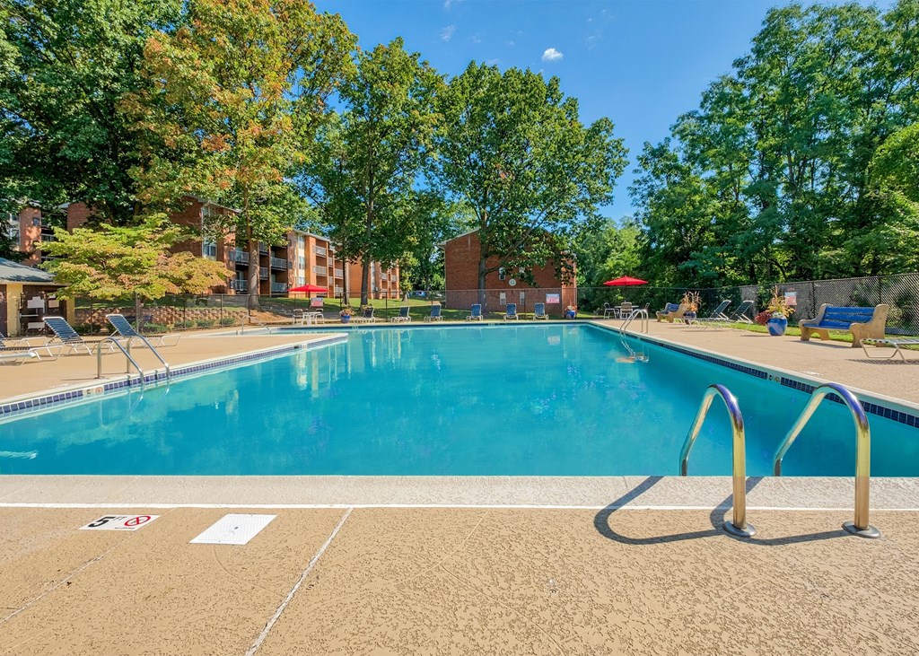 A swimming pool surrounded by trees and a building in the background.