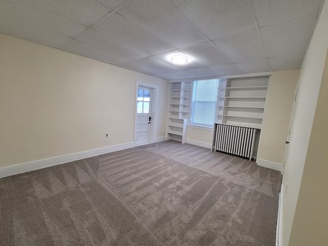 A room with a carpeted floor and a window with blinds.