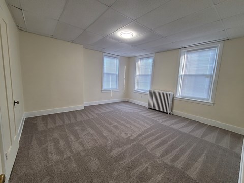 A room with a carpeted floor and a window with blinds.