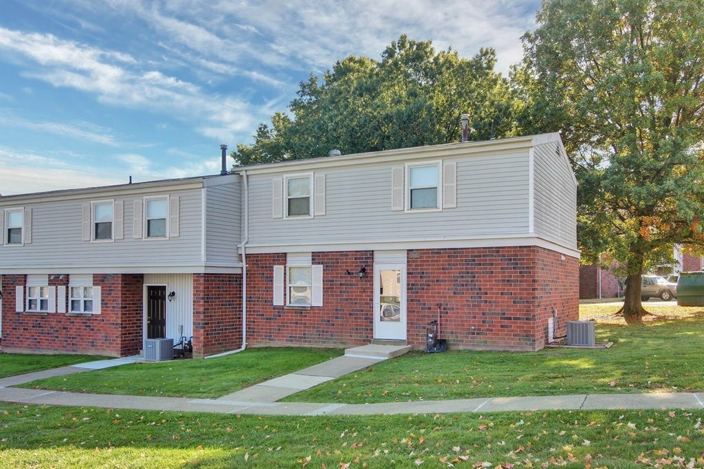 A row of houses with a green lawn in front.