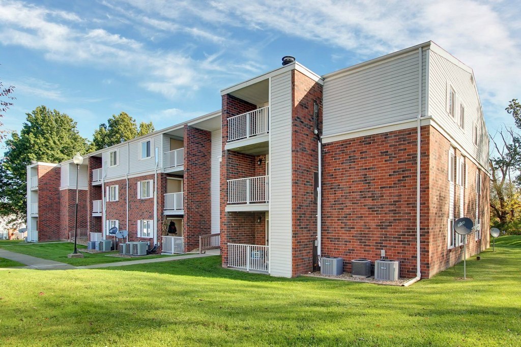 A red brick apartment building with a white balcony.