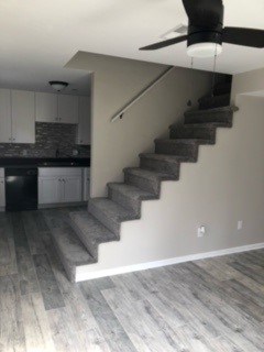 A black fan is hanging from the ceiling in a room with a staircase.