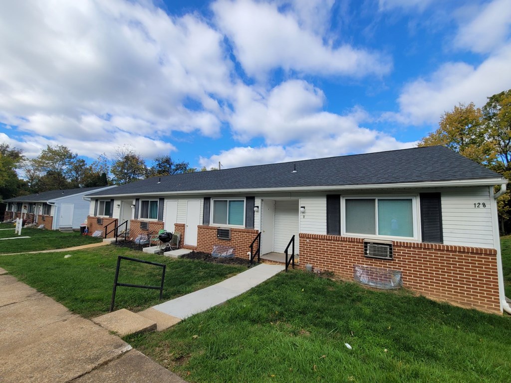 A row of houses with a blue sky and clouds above them.