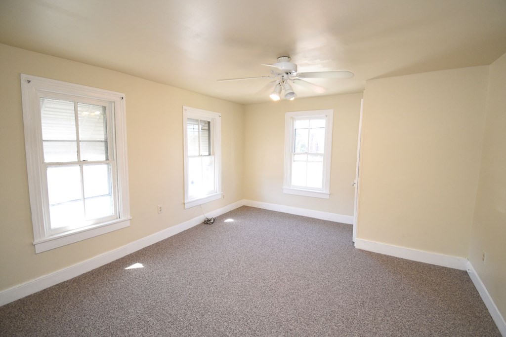 A room with a carpeted floor and a ceiling fan.