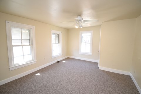 A room with a carpeted floor and a ceiling fan.