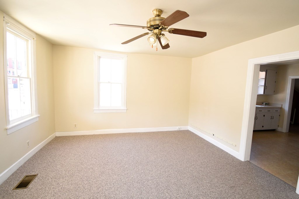 A room with a ceiling fan and two windows.