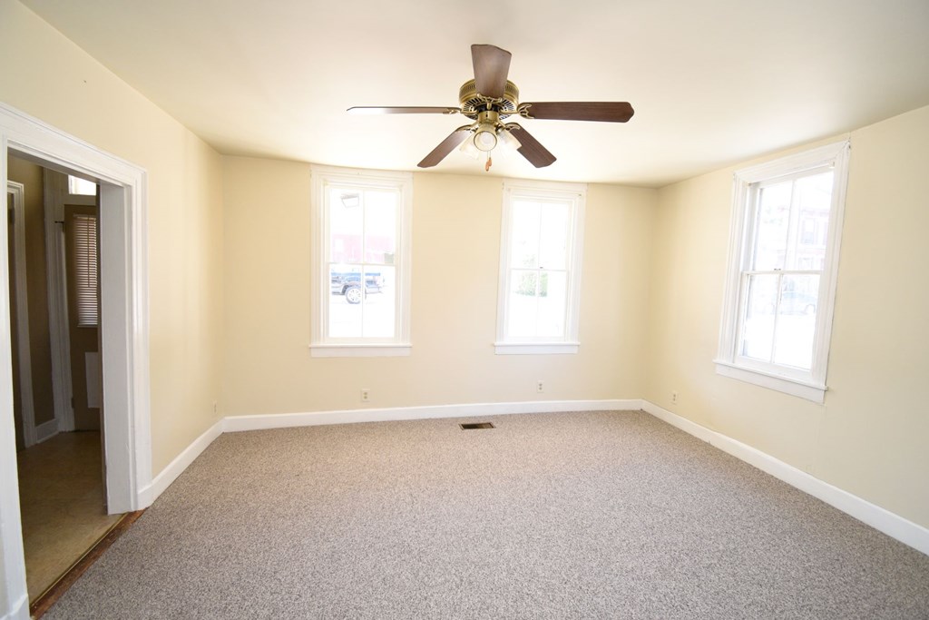 Empty room with a ceiling fan and carpeted floor.