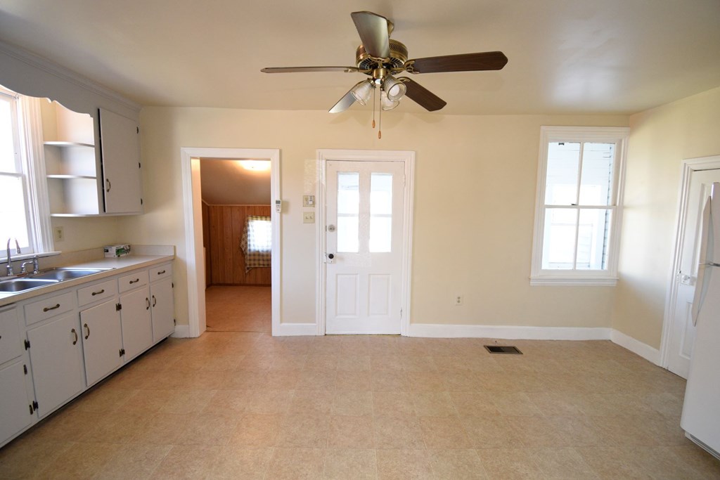 A kitchen with white cabinets and a fan on the ceiling.