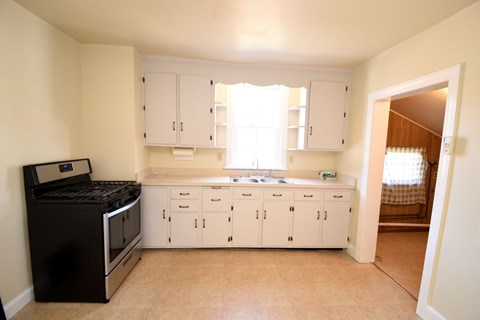 A kitchen with white cabinets and a black stove top oven.