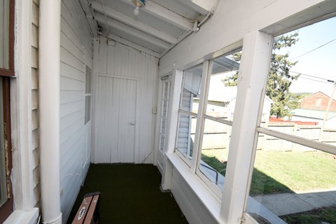 A white porch with a bench and a window.
