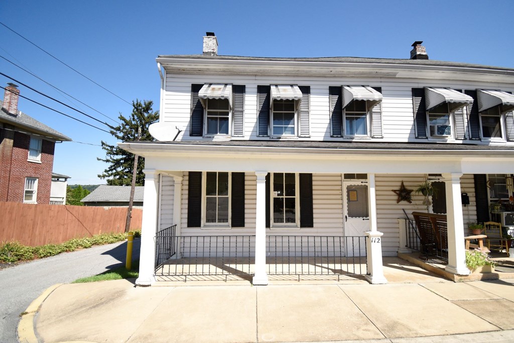 A white house with black shutters and a black gate.