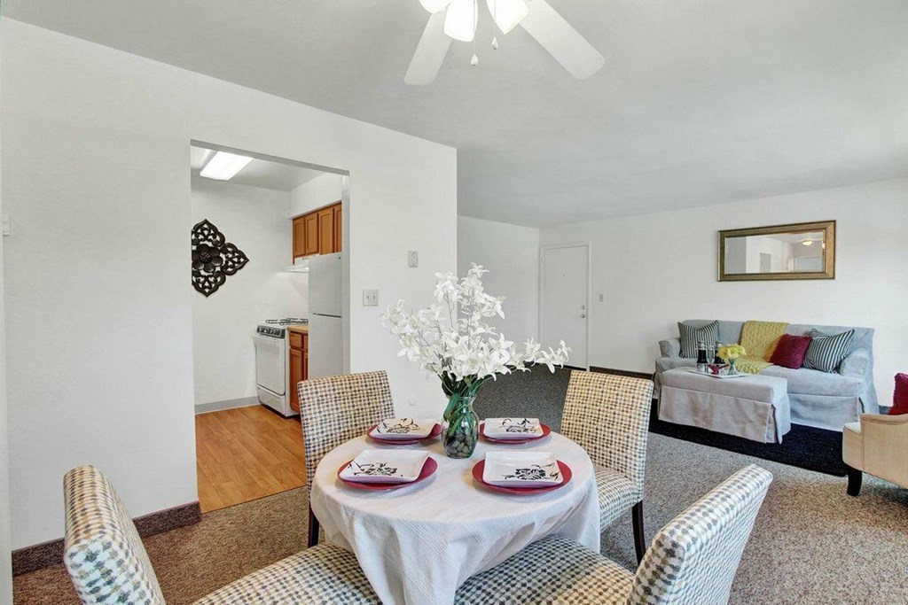 A dining room with a table set for two and chairs around it.