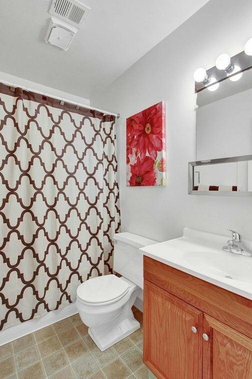 A white toilet sits in a bathroom with a brown and white shower curtain.
