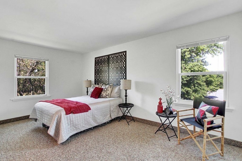 A bedroom with a bed, chair, and table.