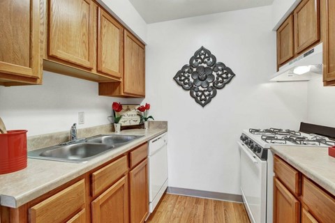 A kitchen with wooden cabinets and a white stove top oven.