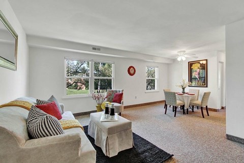 A living room with a couch, a coffee table, and a dining table set up.