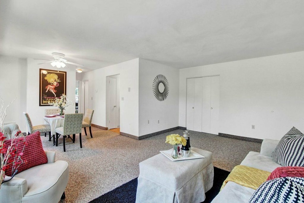 A living room with a grey couch, a white sofa, a coffee table, and a painting on the wall.