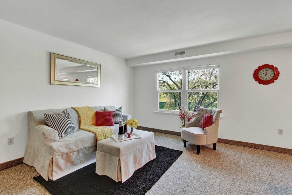 A living room with a couch, chair, and a mirror on the wall.