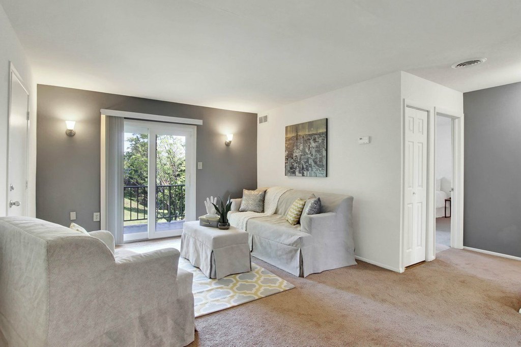 A living room with a couch, chair, and a painting on the wall.