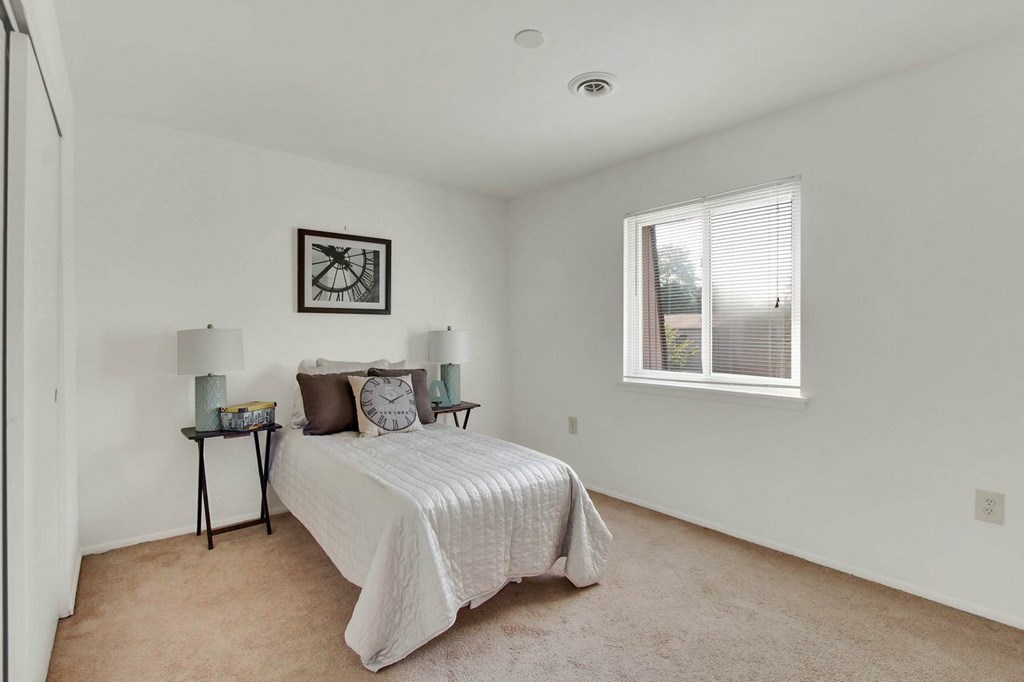 A bedroom with a bed, two lamps, and a picture on the wall.