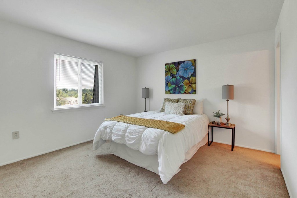 A bedroom with a large bed and a painting on the wall.