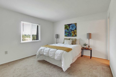 A bedroom with a large bed and a painting on the wall.