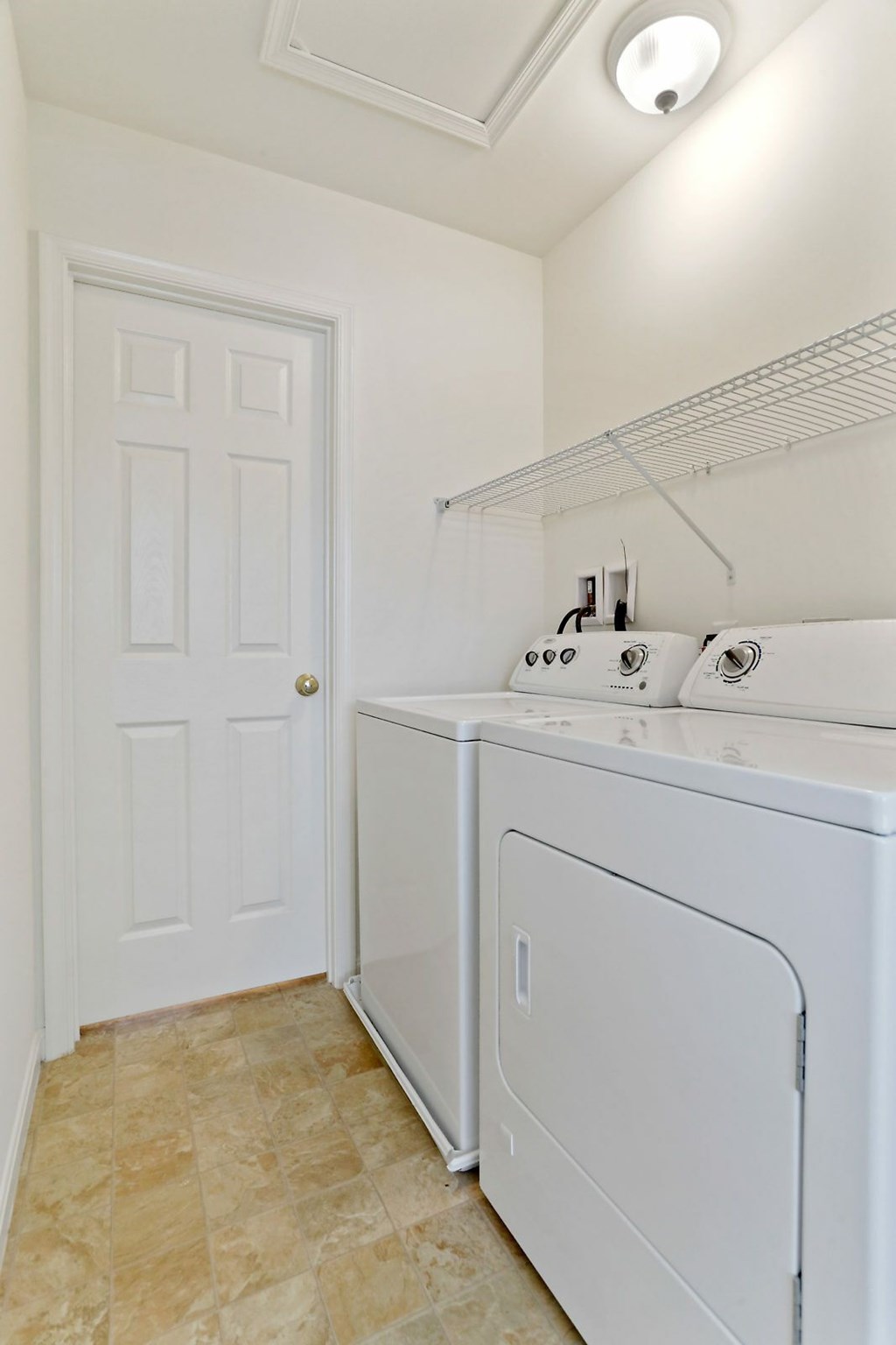 A white laundry room with a door and a washer and dryer.
