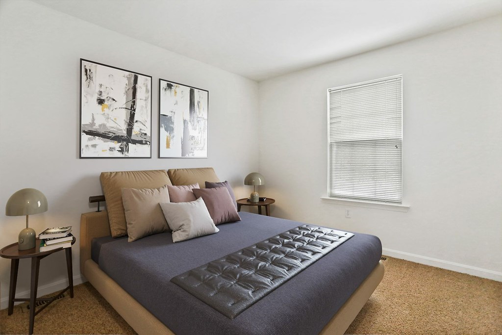 A bedroom with a large bed and two framed pictures on the wall.