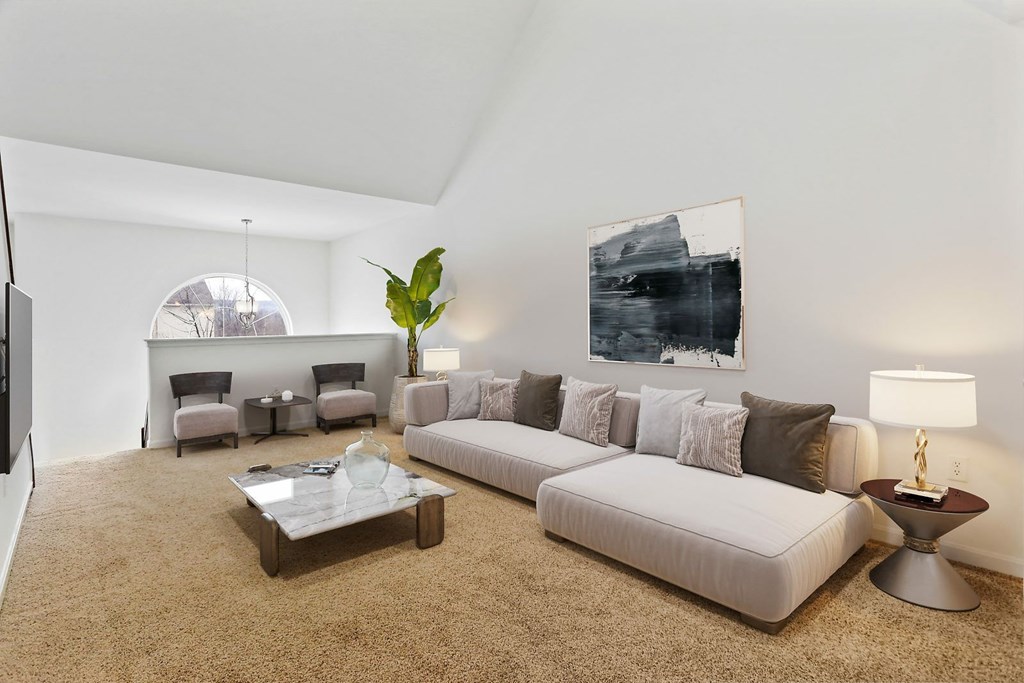 A living room with a white couch, a coffee table, and a large painting on the wall.