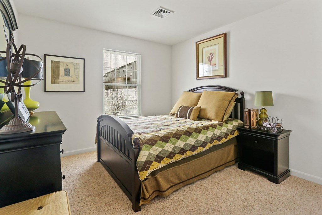 A bedroom with a bed, nightstand, and lamp.