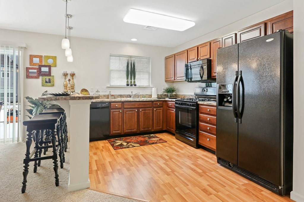 A kitchen with wooden floors and a black refrigerator.