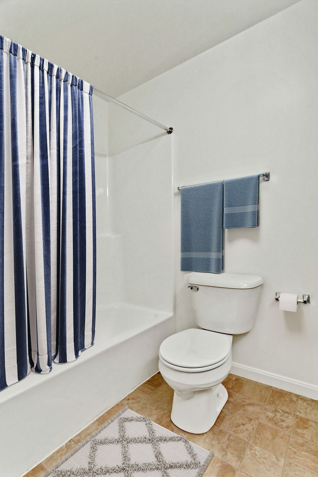 A white toilet in a bathroom with a blue and white striped shower curtain.