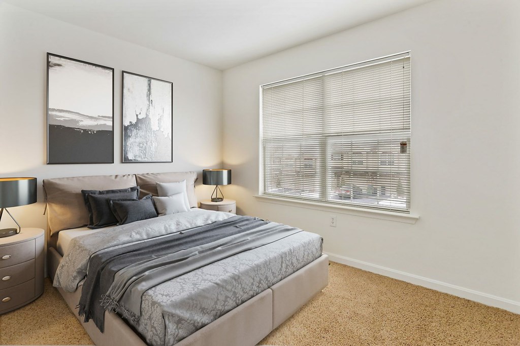 A bedroom with a large bed and two pictures on the wall.