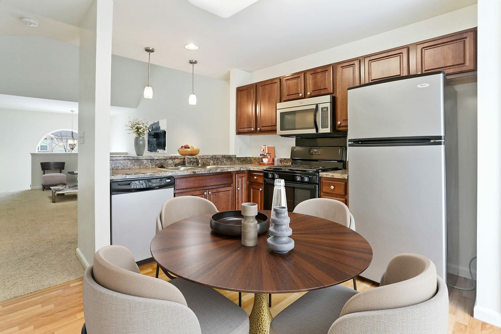 A kitchen with a table and chairs in the foreground and a living room in the background.