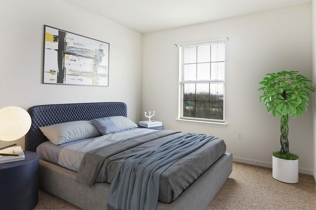 A bedroom with a large bed and a potted plant.